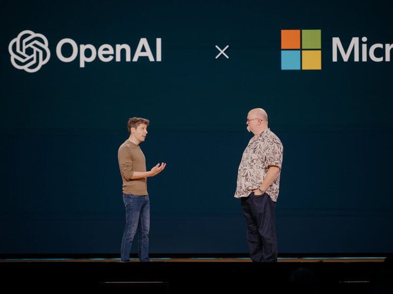 Sam Altman og Satya Nadella på en scene under OpenAI- og Microsoft-logoene
