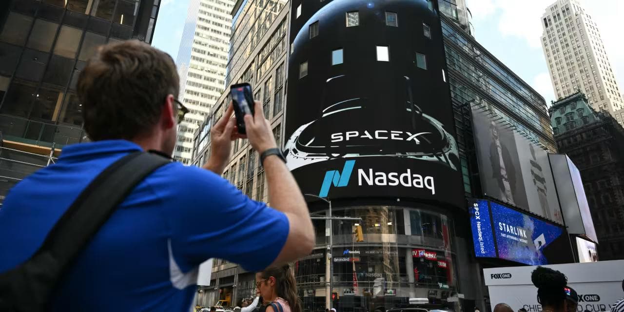 En person fotograferer Nasdaq-tårnet på Times Square med SpaceX-logo på skjermen