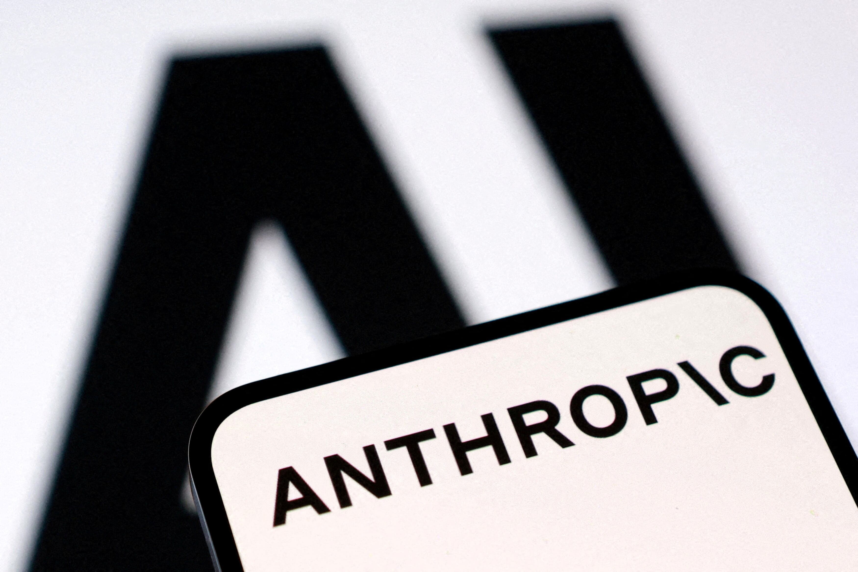 Mobiltelefon med Anthropic-logoen foran store bokstaver som staver AI