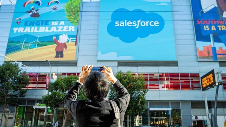 Salesforce-bannere på bygninger og en person som fotograferer med mobil