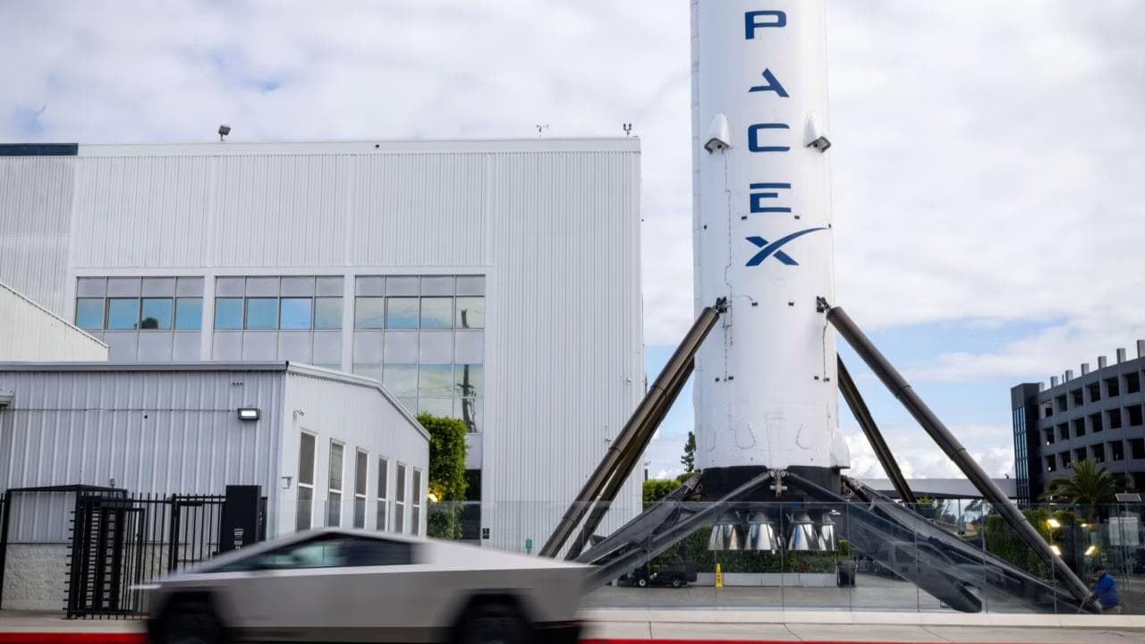 SpaceX-rakettbooster utstilt foran et bygg, med bil i forgrunnen